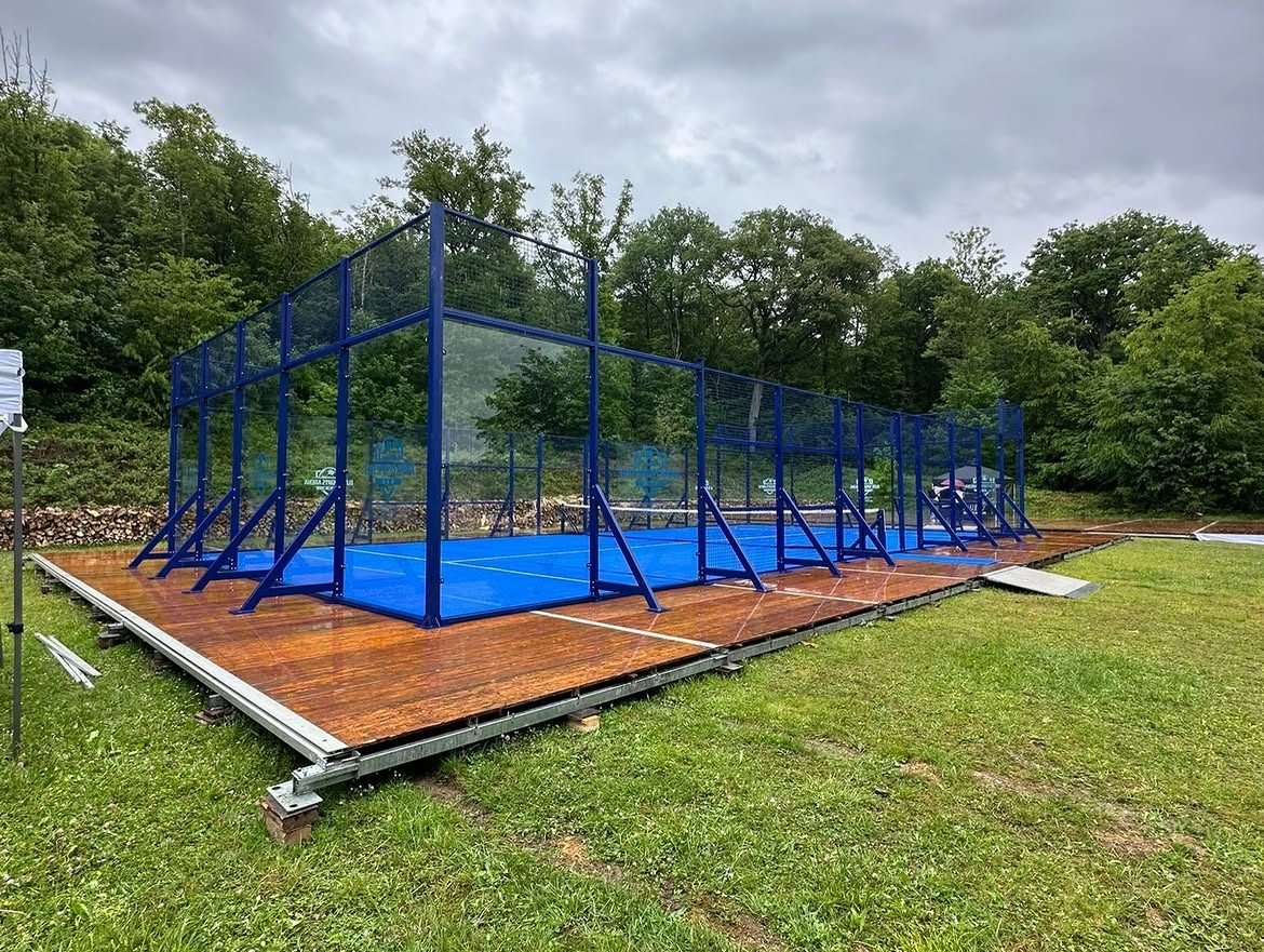 Terrain de padel éphémère monté sur plancher bois, jambes de force visibles sur tout le pourtour