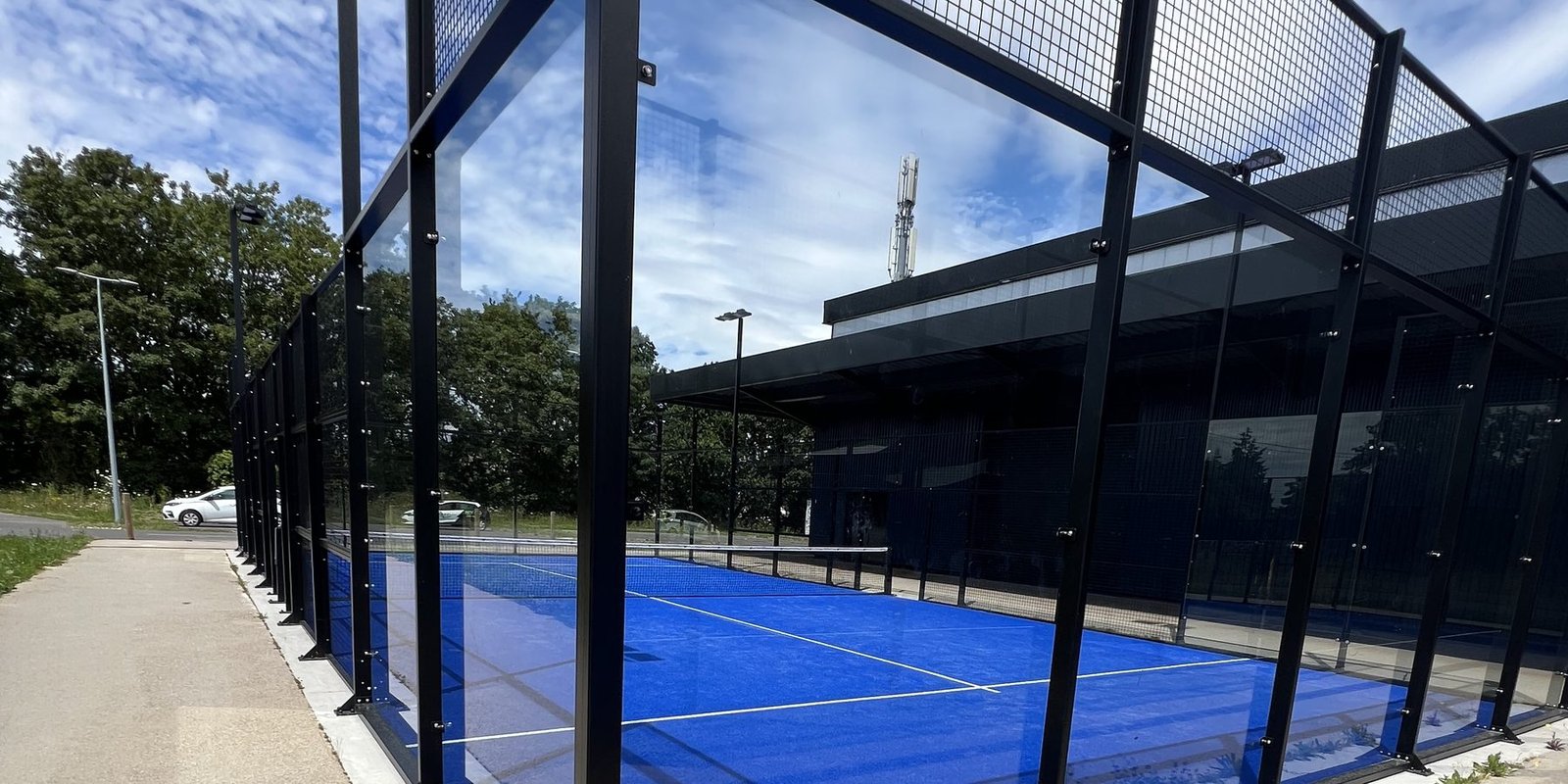 Terrain de padel posé sur sa dalle béton, platines des poteaux boulonnées